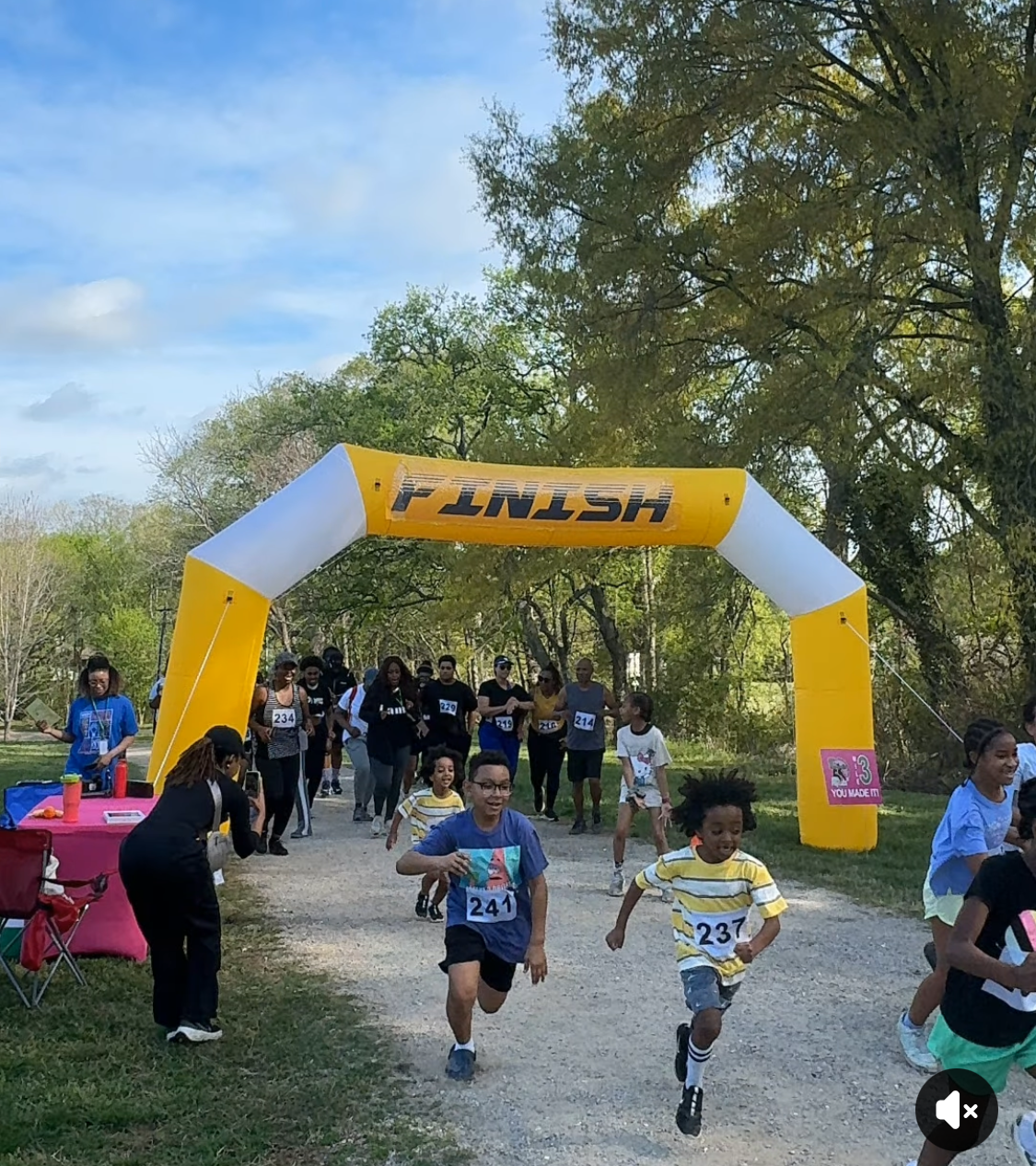 Runners bursting through the yellow FINISH arch at the 2025 Run to Empower Entrepreneurs 5K